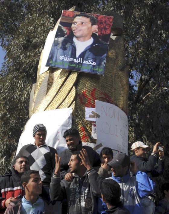 Image: Youths gather at a portrait of Mohamed Bouazizi